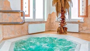 Un jacuzzi en una habitación con paredes de piedra, una ventana y un radiador.