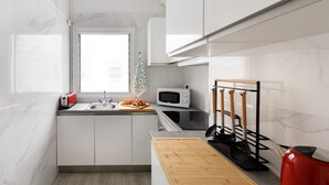 Eine moderne Küche mit weißen Schränken, einer Mikrowelle, einem Toaster und einem Holzschneidebrett.