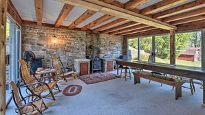 A rustic interior with exposed wooden beams, a stone wall, a fireplace, and a large dining table. - Cozy Home w/ Private Patio & Views, Hiking On-Site (Belleville)
