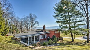 A modern house with a glass extension, a stone chimney, and a view of the water. - Cozy Home w/ Private Patio & Views, Hiking On-Site (Belleville)