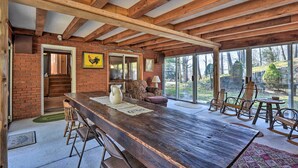 A rustic wooden dining area with a long table, chairs, and a brick wall. - Cozy Home w/ Private Patio & Views, Hiking On-Site (Belleville)