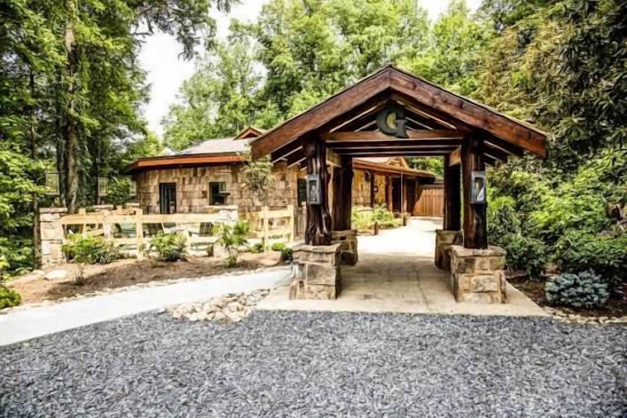 A lodge with a stone exterior, a wooden porch, and a gravel driveway.