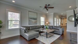 A modern living room with a sectional sofa, a coffee table, and a ceiling fan. - Spacious 4 King Room Belmont Home, 2 Living Rooms | Walk to Belmont & Vanderbilt | Large Dining Table, Smart TVs, Parking, 24 Hr Hospitality | Near Music Row & The Gulch | 2 miles to Broadway (Nashville)