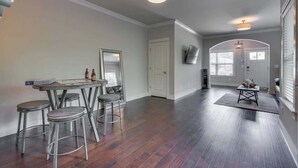 A spacious room with a dining area featuring a table and four stools, a large mirror, and a television mounted on the wall. - Spacious 4 King Room Belmont Home, 2 Living Rooms | Walk to Belmont & Vanderbilt | Large Dining Table, Smart TVs, Parking, 24 Hr Hospitality | Near Music Row & The Gulch | 2 miles to Broadway (Nashville)
