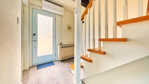 Ein Flur mit einer Holztreppe, einer Tür mit Fenster und einem Heizkörper.