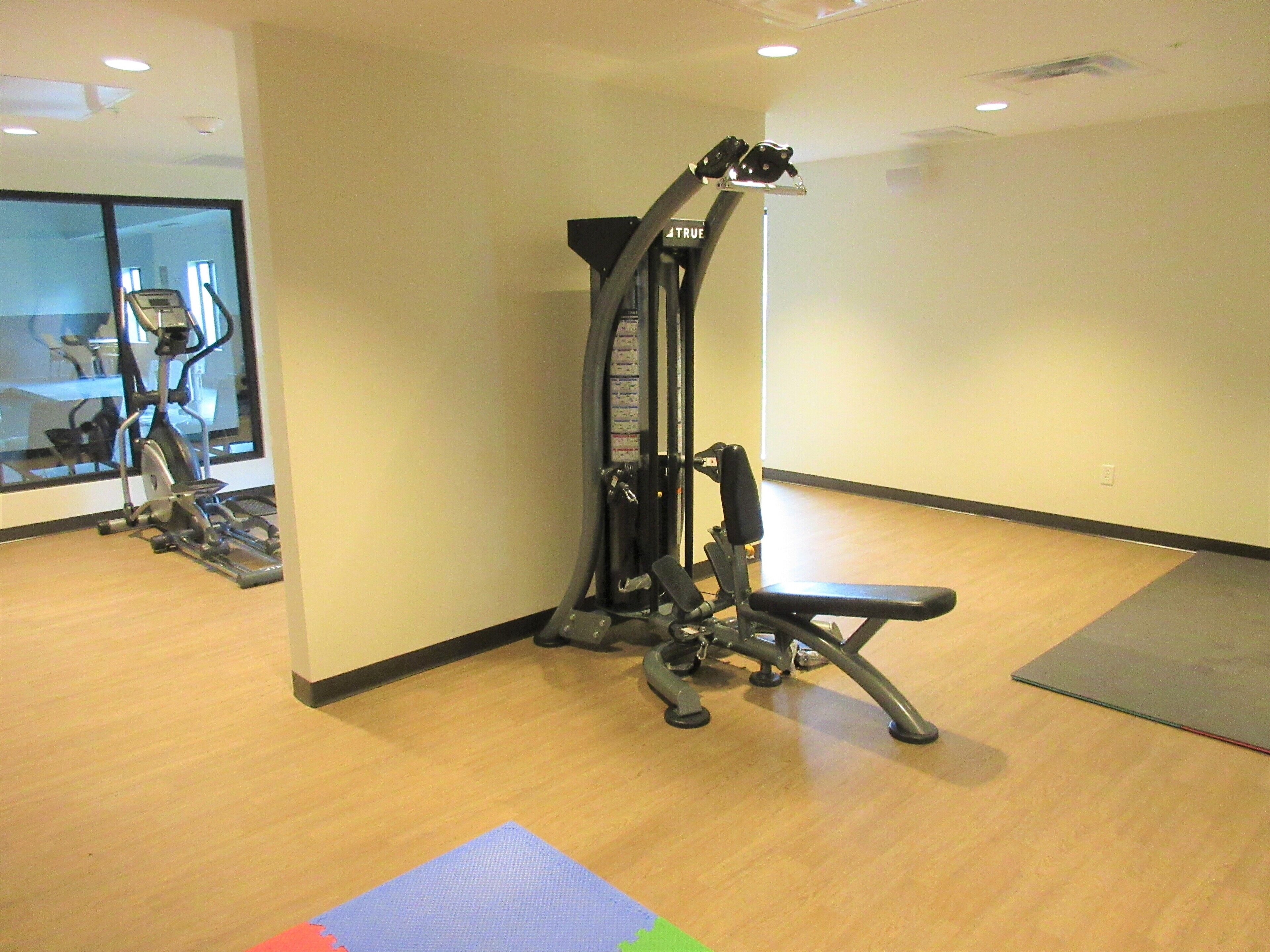 A gym with exercise equipment, a mirror, and a wooden floor.