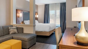 Una habitación de hotel con cama, sofá, escritorio y lámpara.