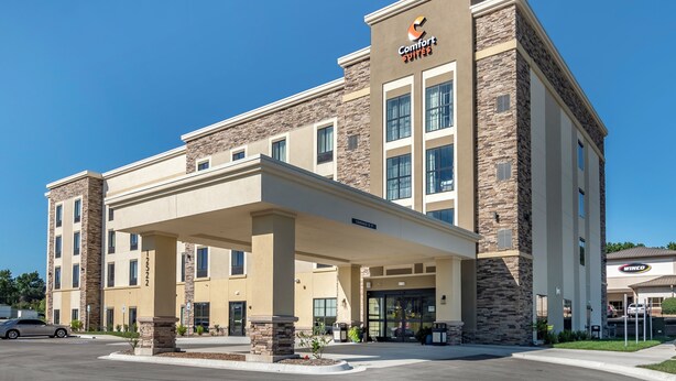 Un hotel con fachada de piedra, un acceso cubierto y un letrero que dice Comfort Suites.
