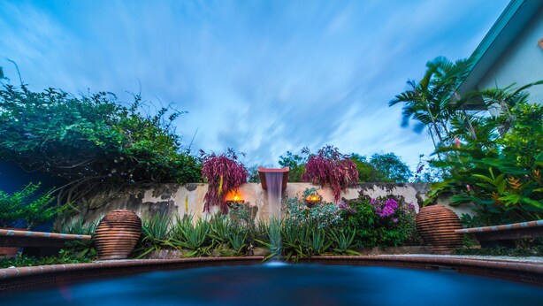 A swimming pool surrounded by lush greenery and decorative plants. - Your home away from home on the Farm, 4 Casitas Bed n Breakfast - Casita 1 (Cabo Rojo)