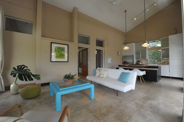 Una sala de estar moderna con un sofá blanco, una mesa de centro azul y un ventanal grande.