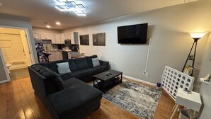 Een moderne woonkamer met een modulaire bank, een salontafel en een aan de muur bevestigde televisie.