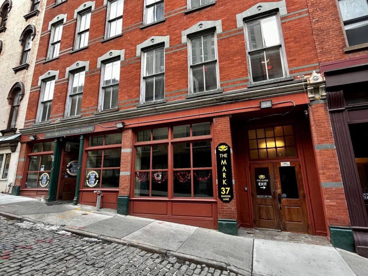A red brick building with large windows and a sign for 'The Mark 37 Maiden Lane'.