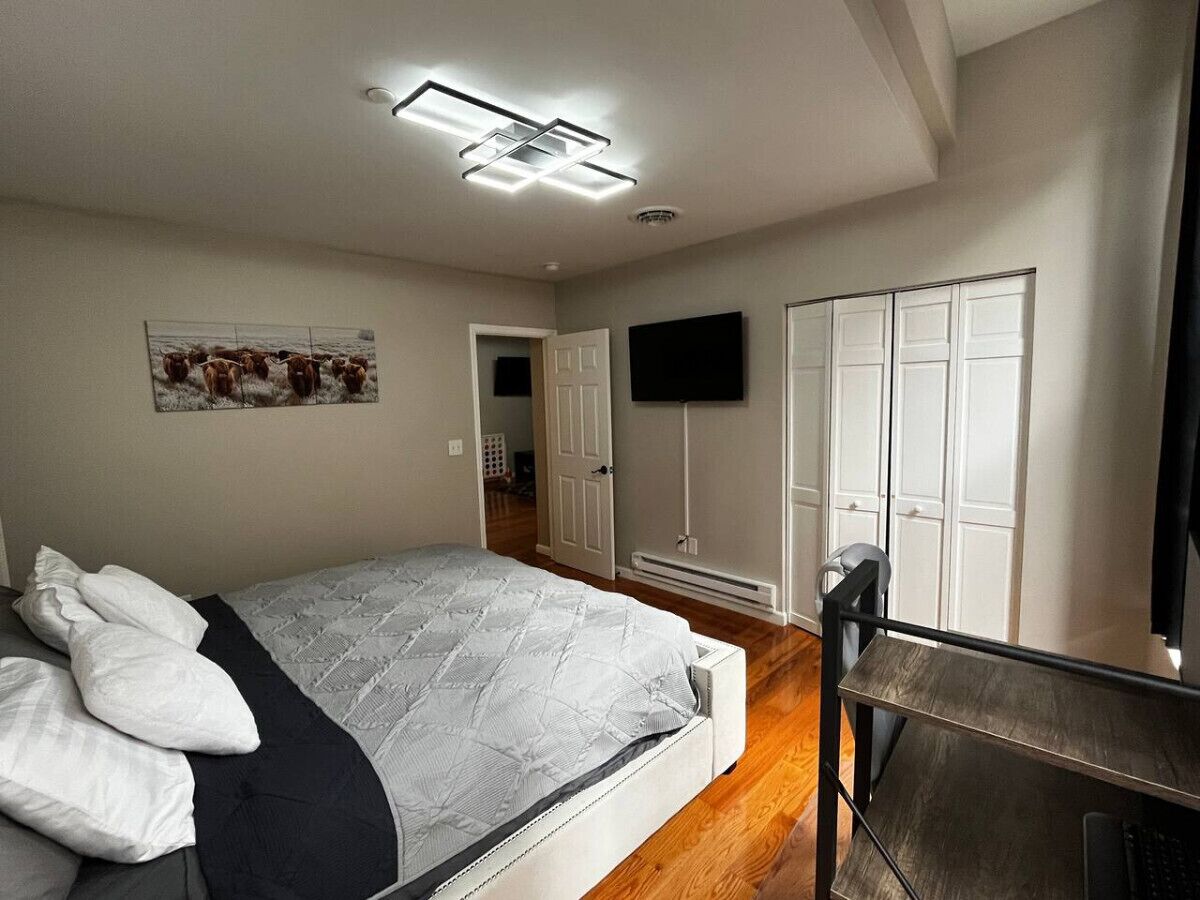 A bedroom with a bed, a desk, a TV, and a wardrobe.