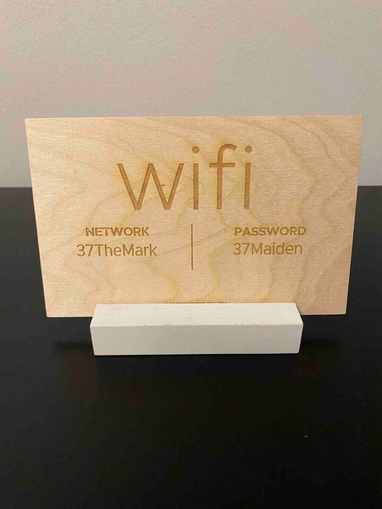 A wooden sign with the word "Wifi" and network and password information.