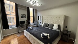 Een moderne slaapkamer met een groot bed, een bureau en een stoel.