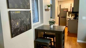 Una cocina moderna con horno empotrado, un comedor con mesa y sillas, y una ventana con una obra de arte en la pared.
