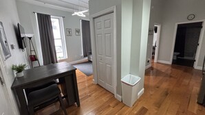 Une pièce avec un plancher en bois, une table à manger avec des chaises, une porte blanche et une poubelle.