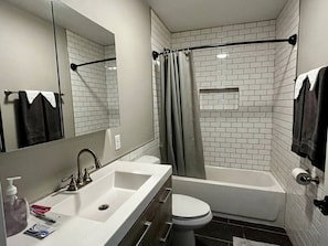 A modern bathroom with a white sink, toilet, and bathtub. - Downtown Albany 1 Bed Penthouse @ Maiden Lane (Albany)