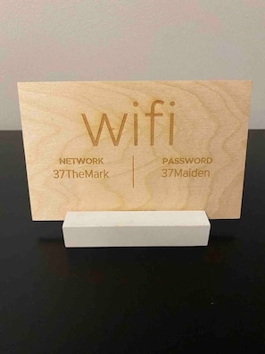 A wooden sign with the word "Wifi" and network and password information. - Downtown Albany 1 Bed Penthouse @ Maiden Lane (Albany)