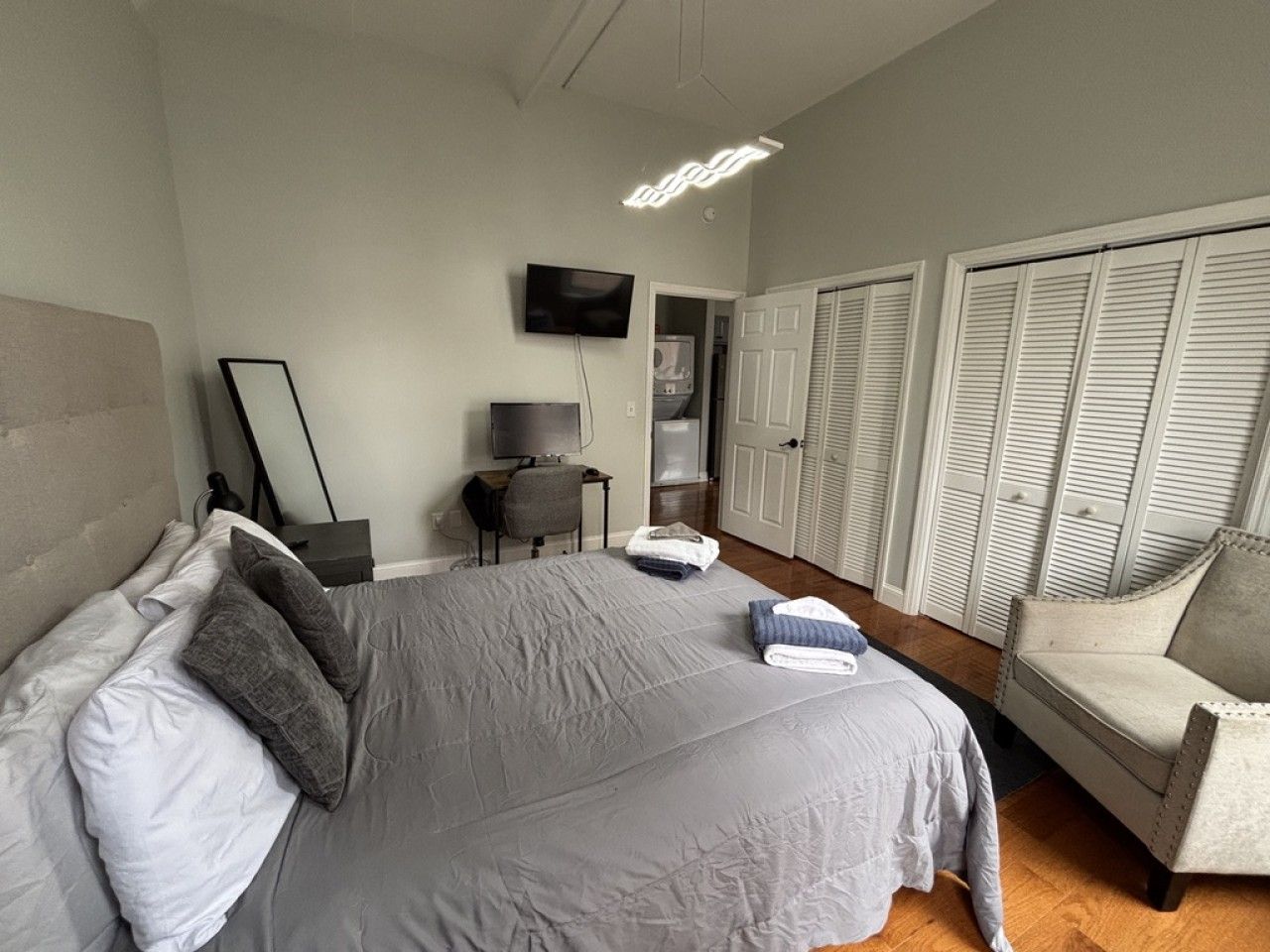 A bedroom with a bed, a chair, a television, and a wardrobe.