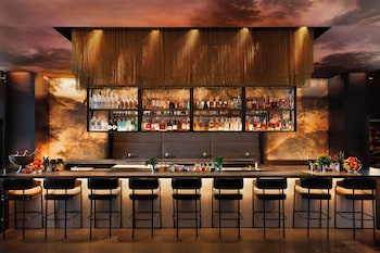 A hotel room with a large bed, a TV, a bench, and a city view. at W Nashville