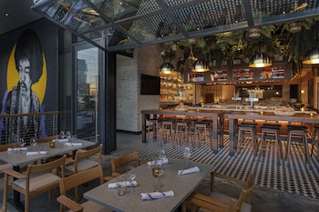 A bar area with a long counter, multiple shelves of bottles, and several bar stools. at W Nashville