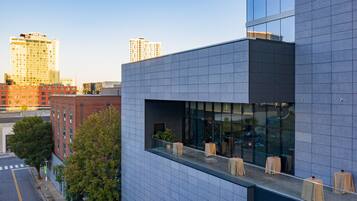 A modern building with a glass facade and a rooftop terrace with tables and chairs.