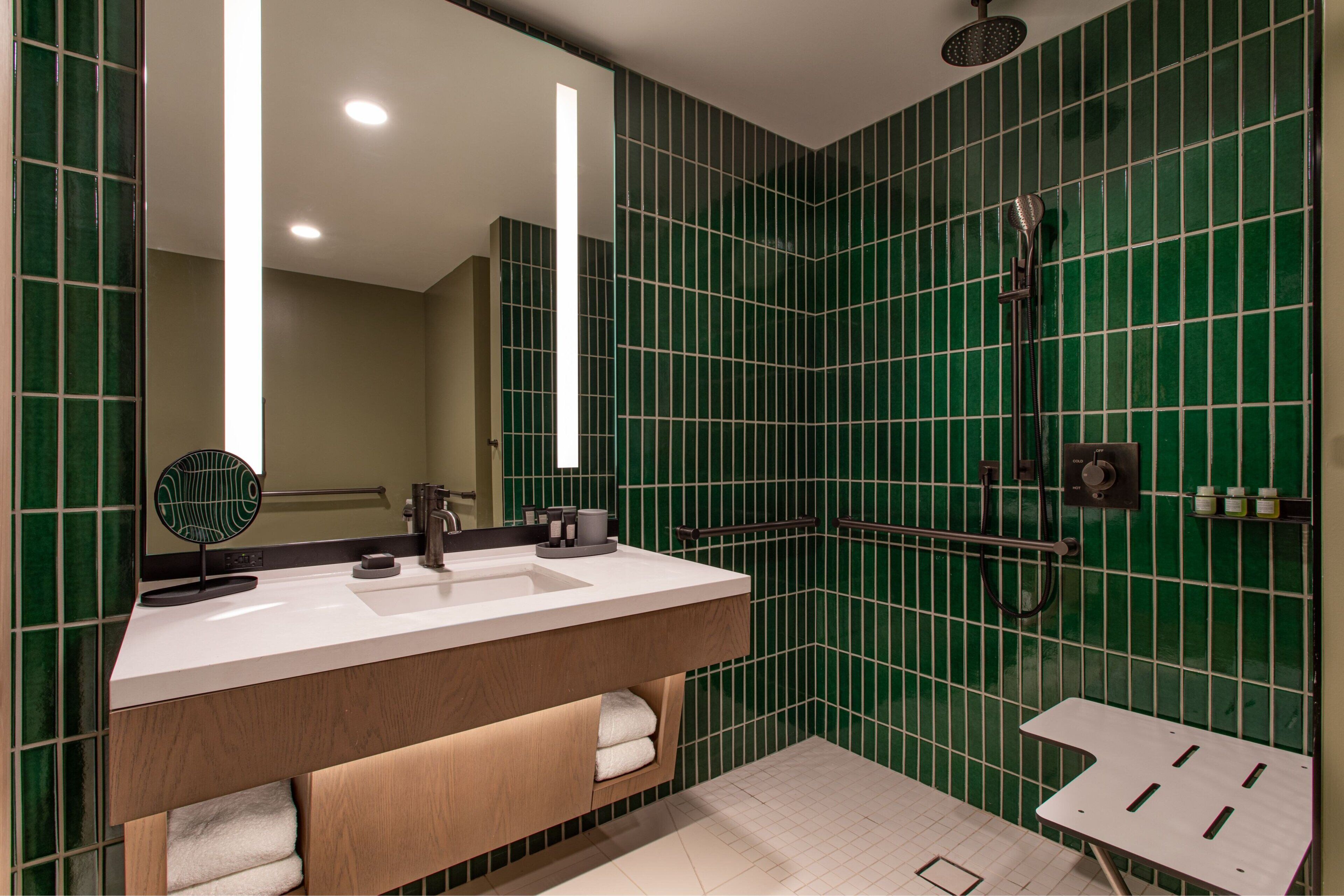 A modern bathroom with a large mirror, a sink, and a shower.
