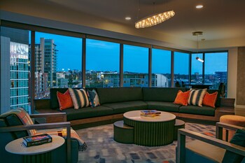 Relax in this stylish living room with a large sofa, coffee table, and side table, offering a view of the city. at W Nashville