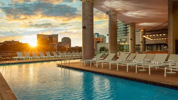Una piscina al aire libre, camas de piscina con cargo, sombrillas