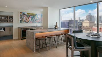 Cocina moderna con una isla central, taburetes de bar y un amplio ventanal con vista a la ciudad.