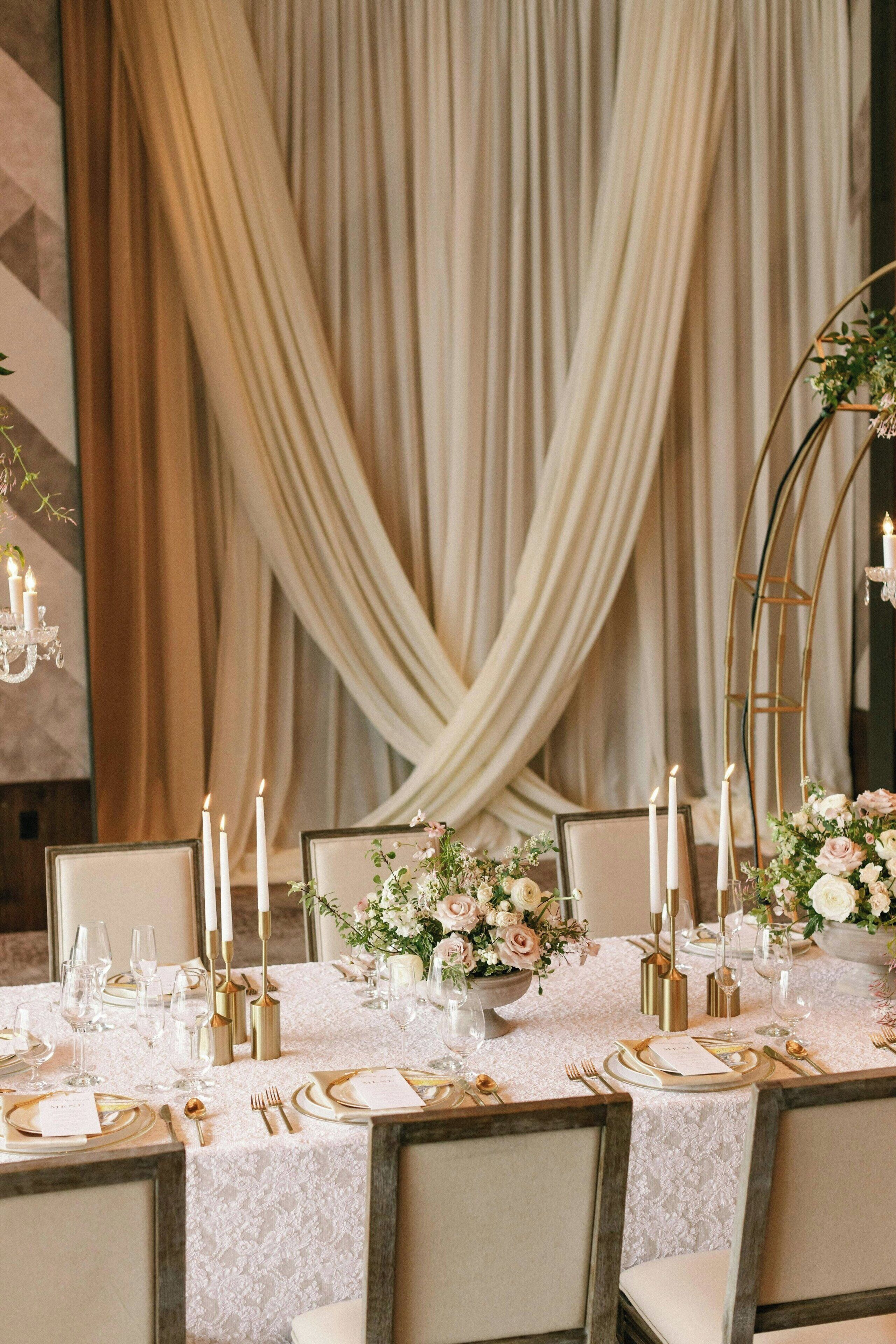 A formal dining table set with white tablecloth, gold cutlery, and candles.