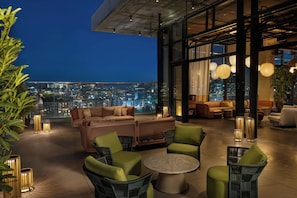 A rooftop lounge with a city view, furnished with sofas, chairs, and a round table. - W Nashville (Nashville)