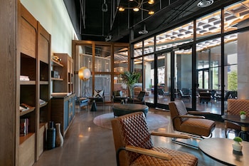 Relax in a stylish lounge area with cushioned chairs and a round table, surrounded by bookshelves and decorative items. at W Nashville