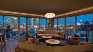 A modern living room with a large sectional sofa, multiple round coffee tables, and a city view through large windows. - W Nashville (Nashville)