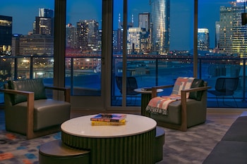 Enjoy a panoramic city view from the comfort of this stylish room, featuring a seating area with armchairs and a coffee table. at W Nashville