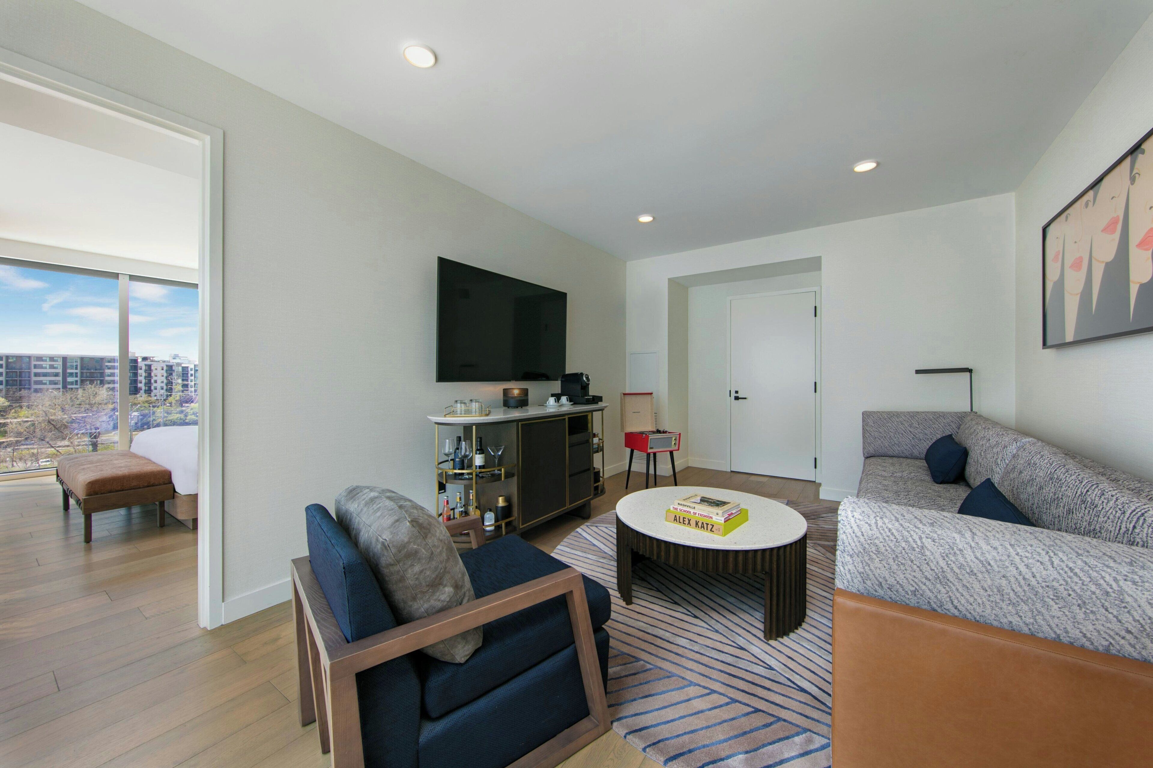 A modern living room with a sofa, a coffee table, and a TV mounted on the wall.