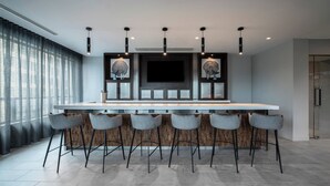 Una cocina moderna con una isla grande, taburetes de bar e iluminación colgante.