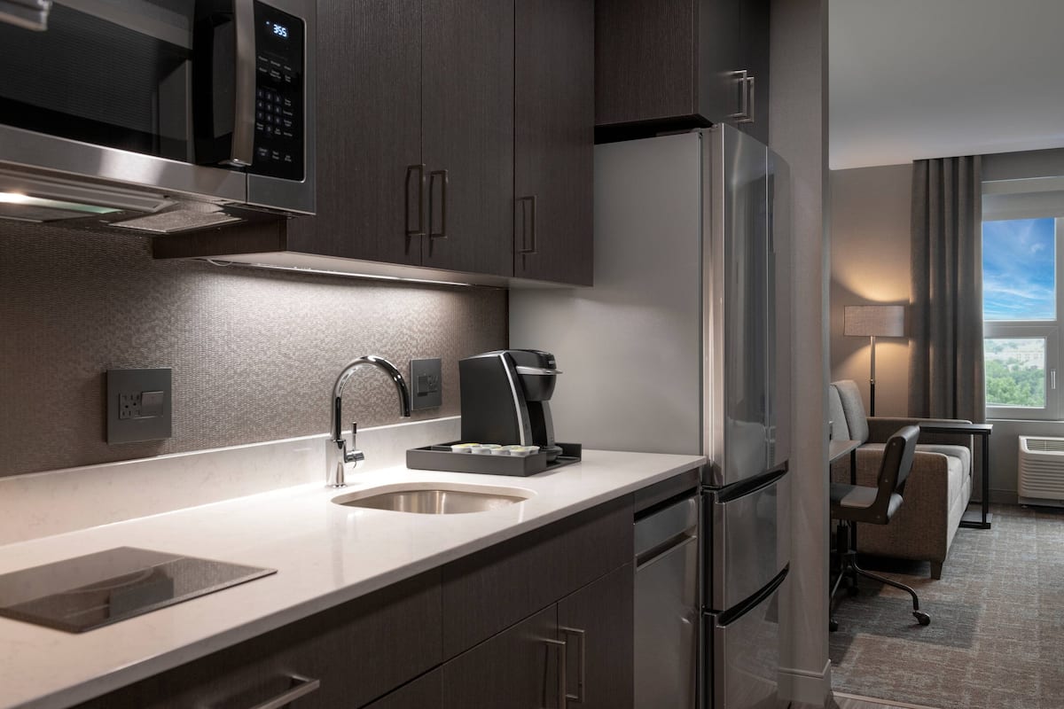 A modern kitchen with stainless steel appliances, a built-in coffee maker, and a seating area with a view.