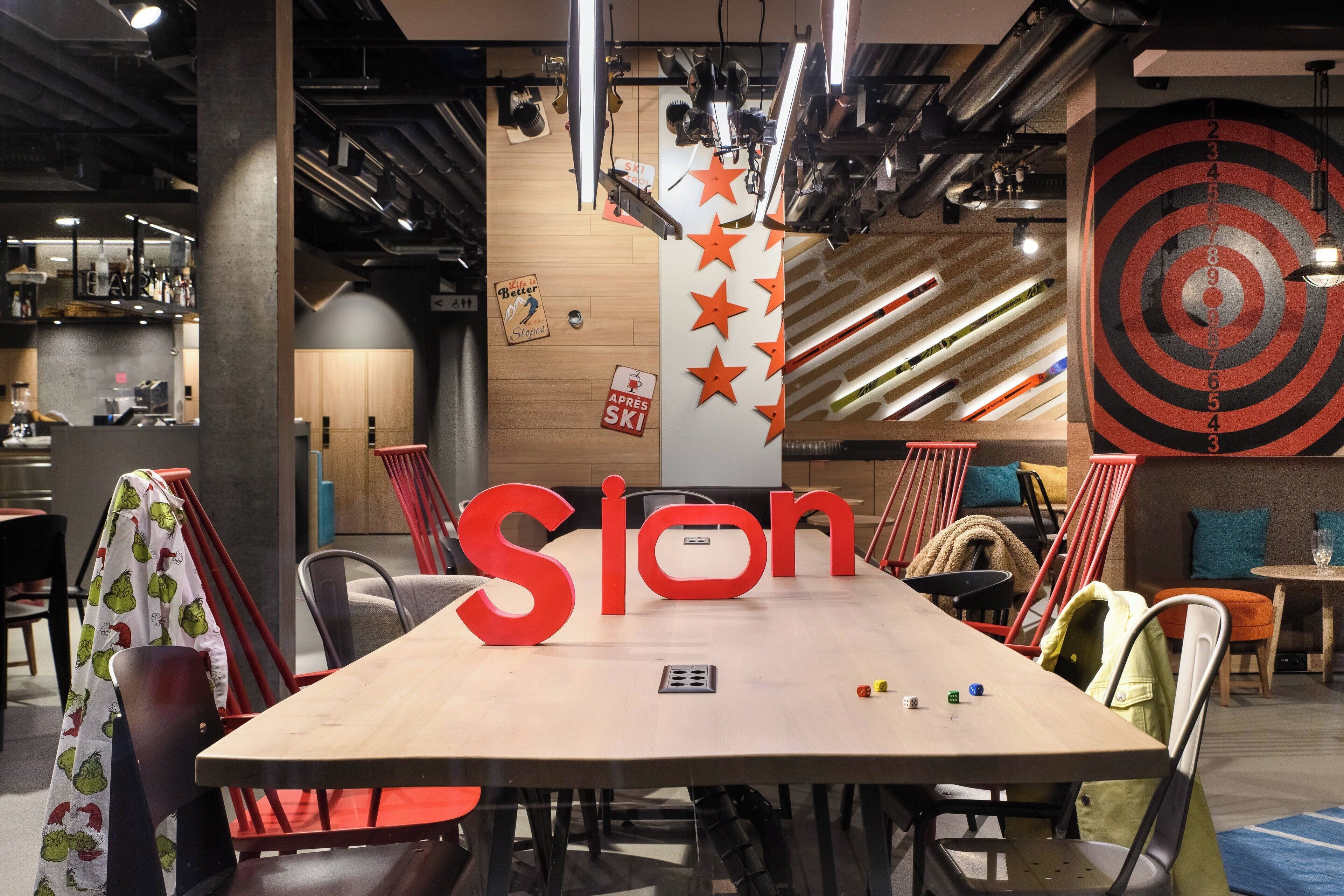 A conference room with a large table, red chairs, and a 'Ston' sign.