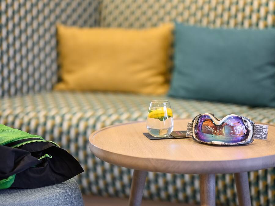 A round wooden table with a pair of goggles and a glass of water on it.
