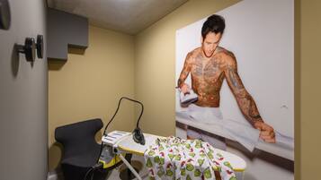 Cozy retreat with a compact bed, large mirror, and ironing station.