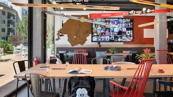 Un comedor moderno con una mesa grande, sillas rojas y vistas de la ciudad a través de amplias ventanas.
