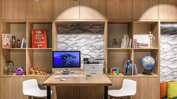 A study area with a desk, two chairs, a computer, shelves with books, decorative items, and a globe.