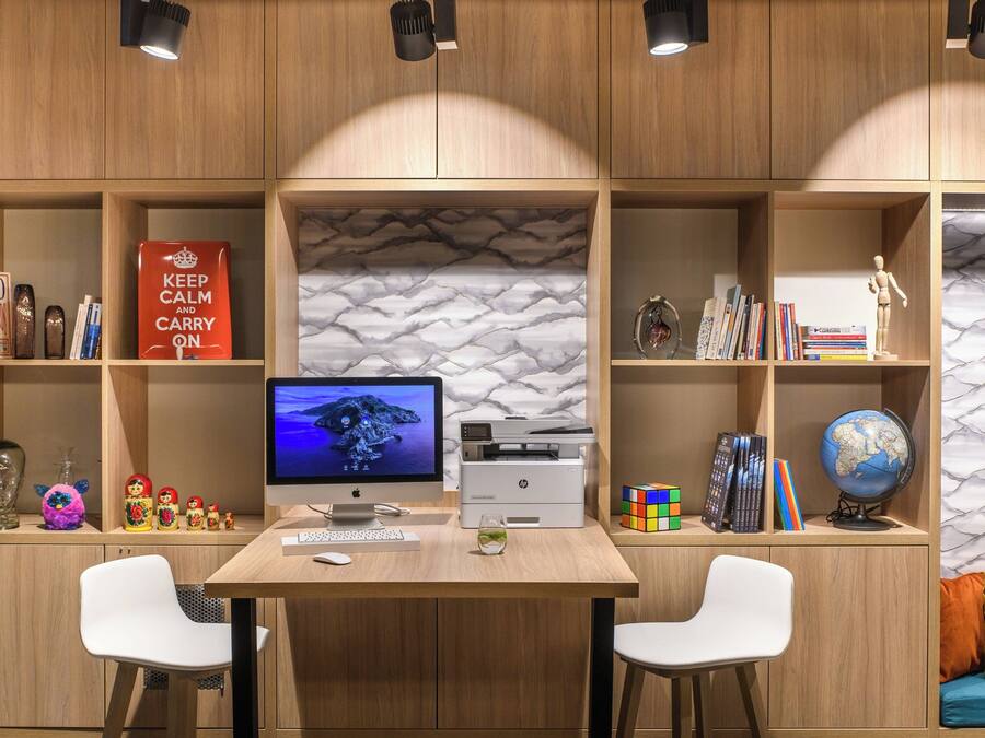 Un espace de travail comprenant un bureau, deux chaises, un ordinateur, des étagères remplies de livres, des objets décoratifs et un globe terrestre.