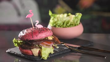 Un hamburger surmonté d’un flamant rose, le tout posé sur une planche d’ardoise noire.