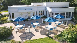 A white building with a patio area featuring outdoor seating and blue umbrellas.