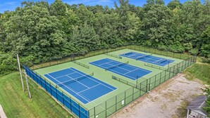 A tennis court complex surrounded by dense trees.
