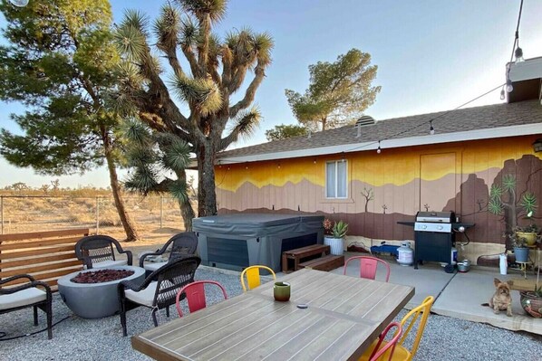 An outdoor patio with a wooden table, chairs, a barbecue grill, and a hot tub. - The Desert Peacock, Hot Tub, Central AC & VIEWS (Yucca Valley)