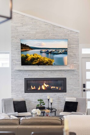 A modern living room with a fireplace, a mounted TV, and a cozy seating area. - Coeur d'Alene Townhome Modern New Downtown Shops Beach (CDA)